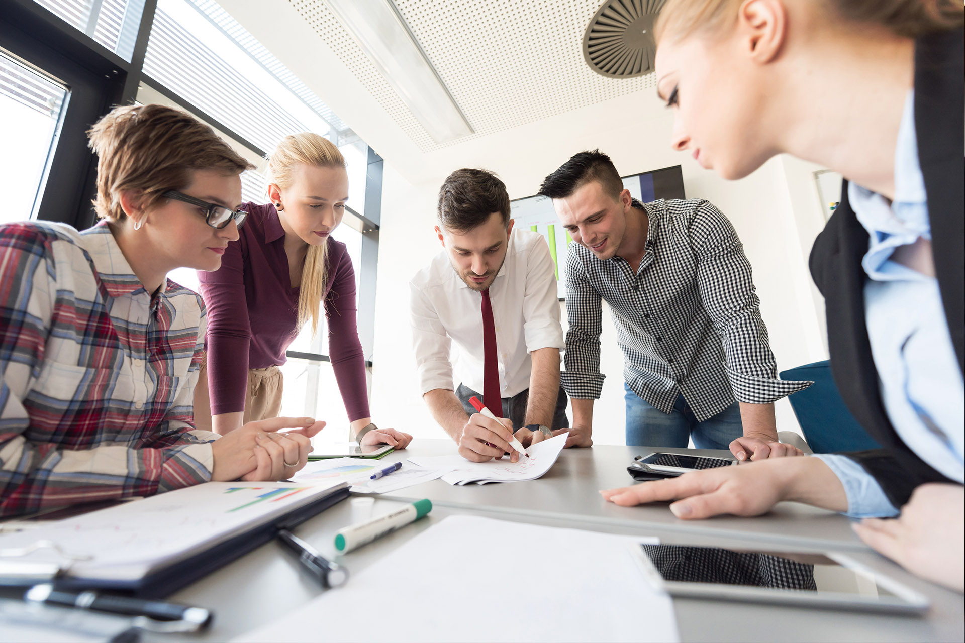 Smiling team leader with employees listening to businesswoman at corporate meeting, sitting in modern boardroom, happy colleagues partners discussing project strategy, sharing startup ideas